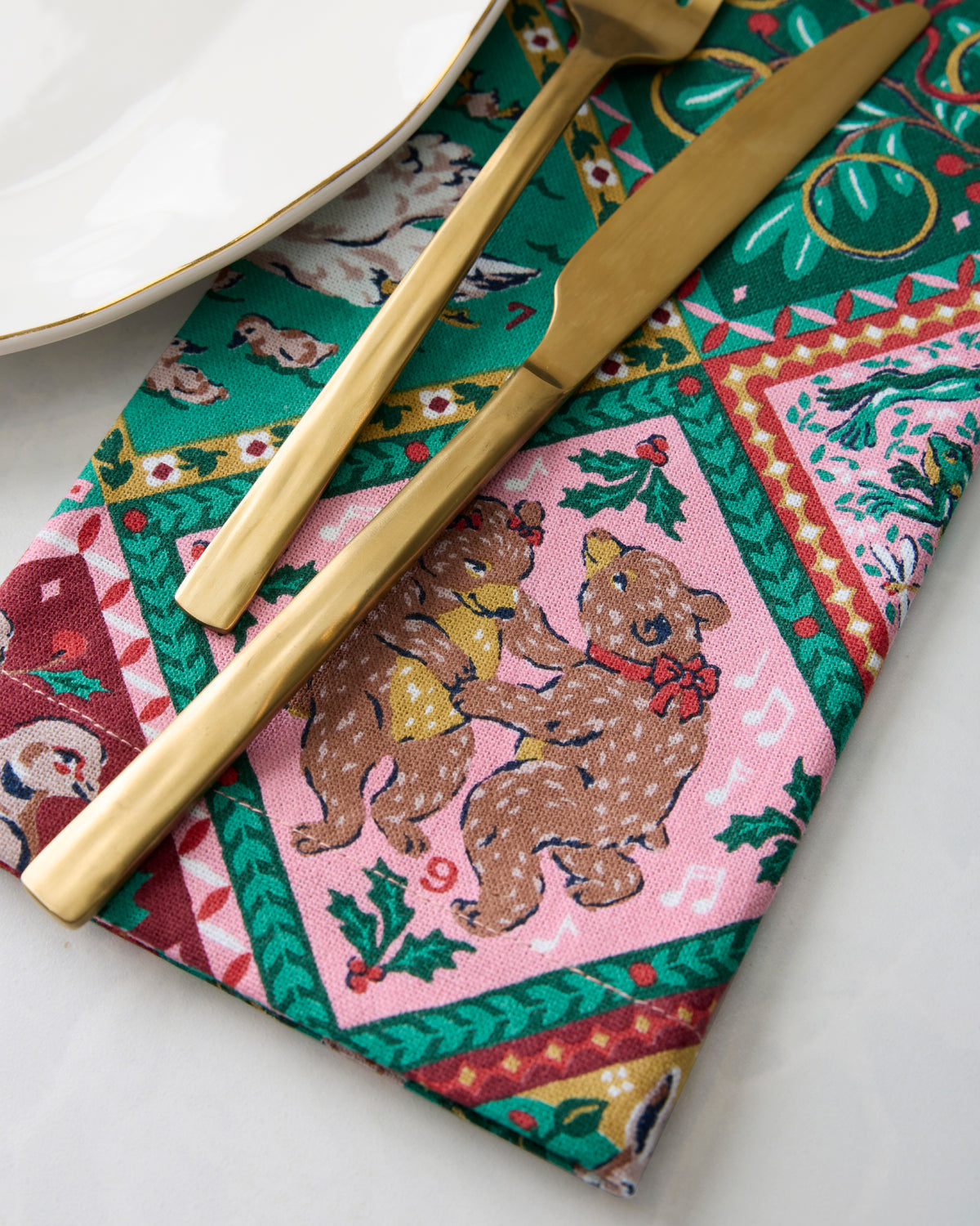 Close-up of a printed dinner napkin with a fork and knife beside a plate.