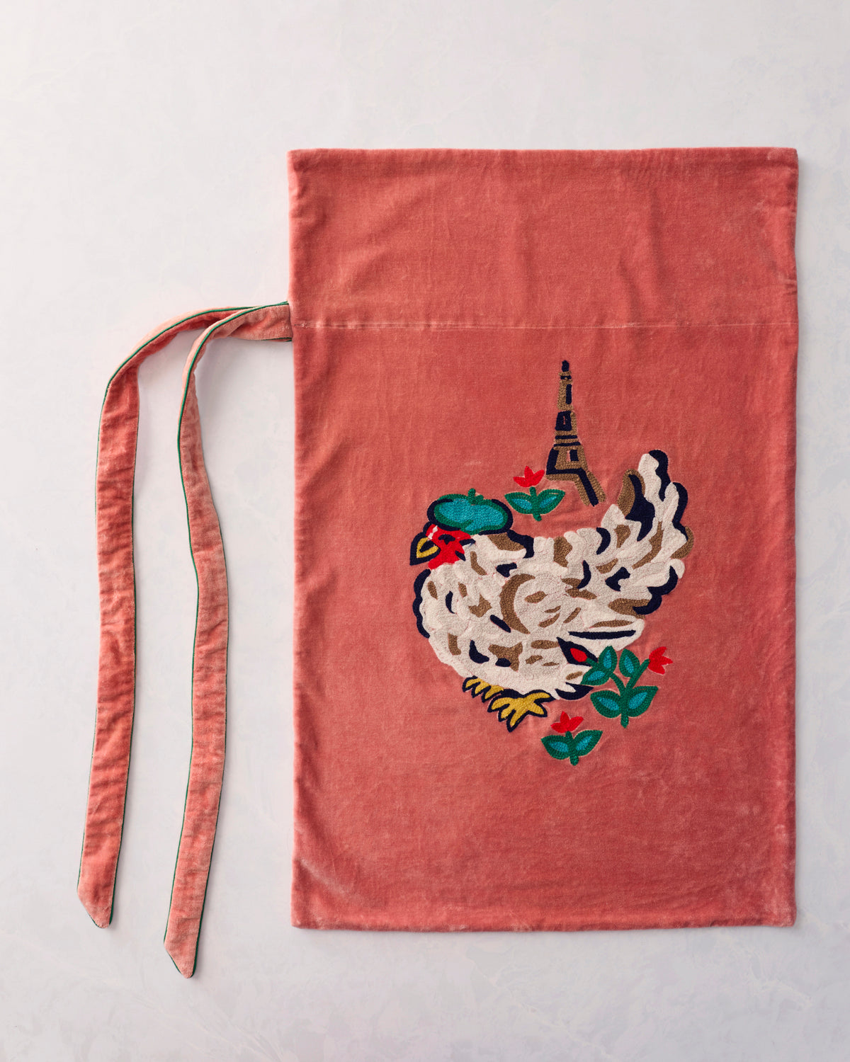 Flat view of a coral gift sack with an embroidered white hen and floral details, plus two ties.