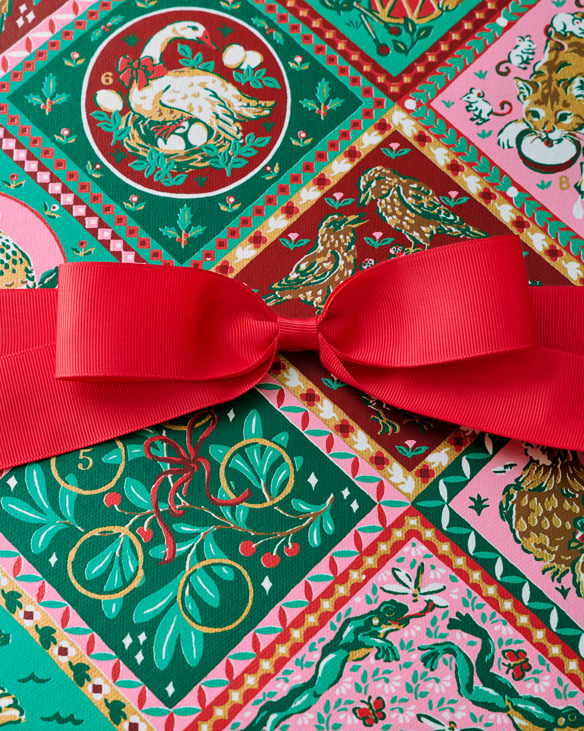 Close-up of the multicolored vintage holiday print and red ribbon on the 12 Days of Christmas gift box