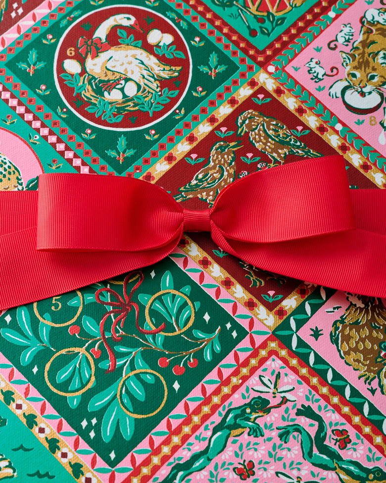 Close-up of the multicolored vintage holiday print and red ribbon on the 12 Days of Christmas gift box