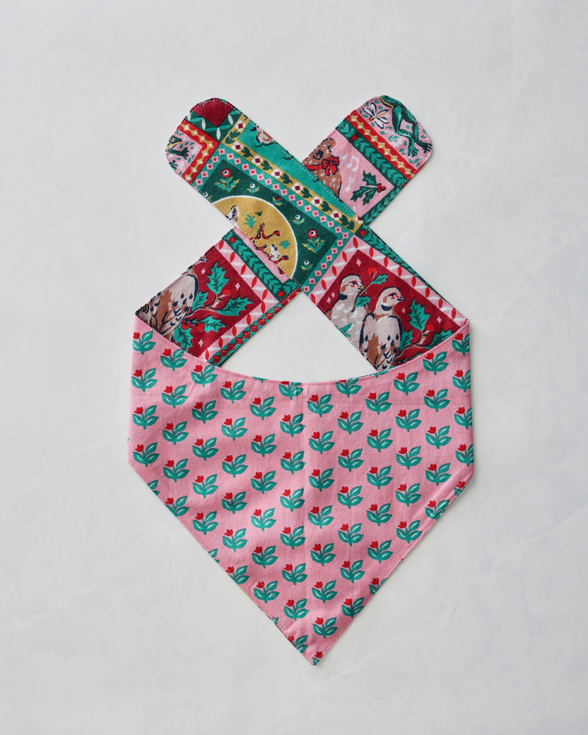 Pet bandana laid flat with pink repeating floral fabric and colorful vintage holiday print on the tie straps.