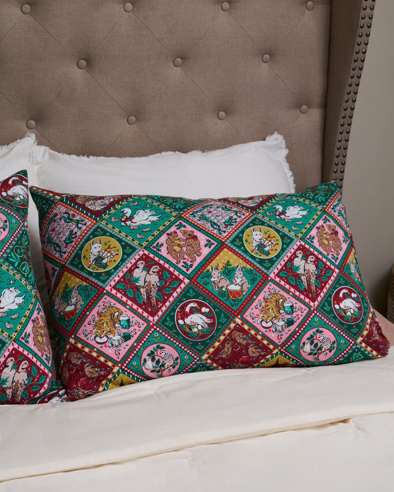 Christmas-themed pillowcases displayed on a bed, featuring colorful diamond-patterned illustrations of holiday scenes and animals.