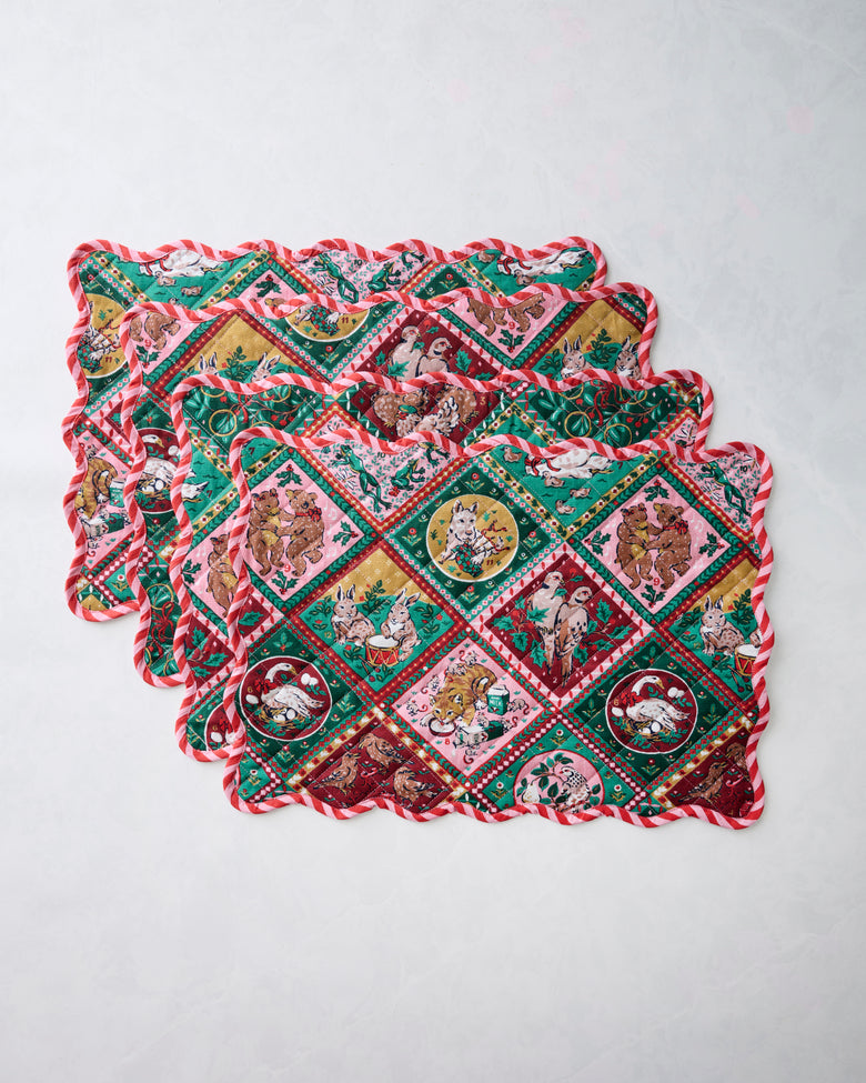 Set of four Christmas-patterned placemats stacked and overlapping on a light background.