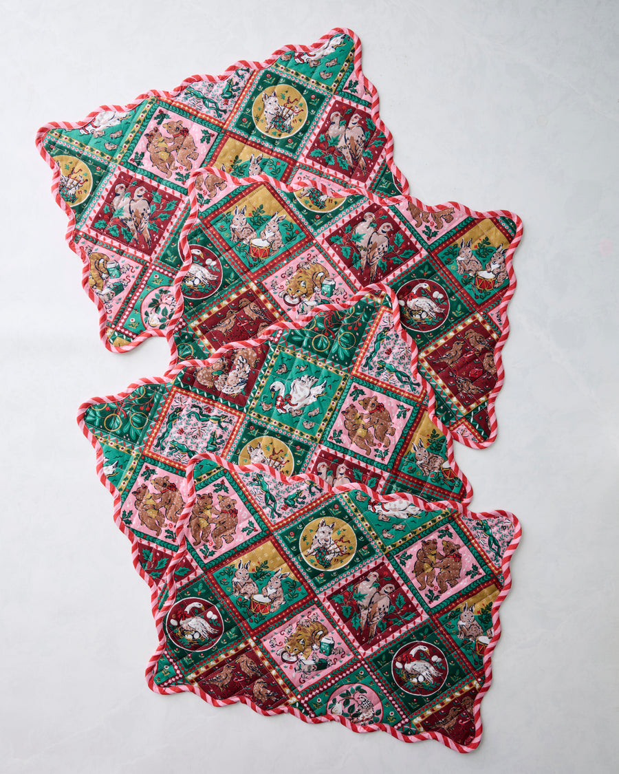 Four Christmas-patterned placemats arranged in an overlapping diagonal layout.