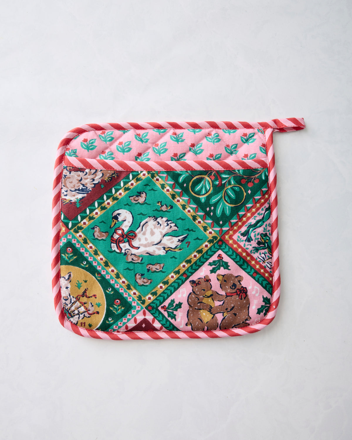 Front of a square Christmas-themed pot holder with illustrated animal scenes, repeating leaf pattern, and red-and-white striped edging.