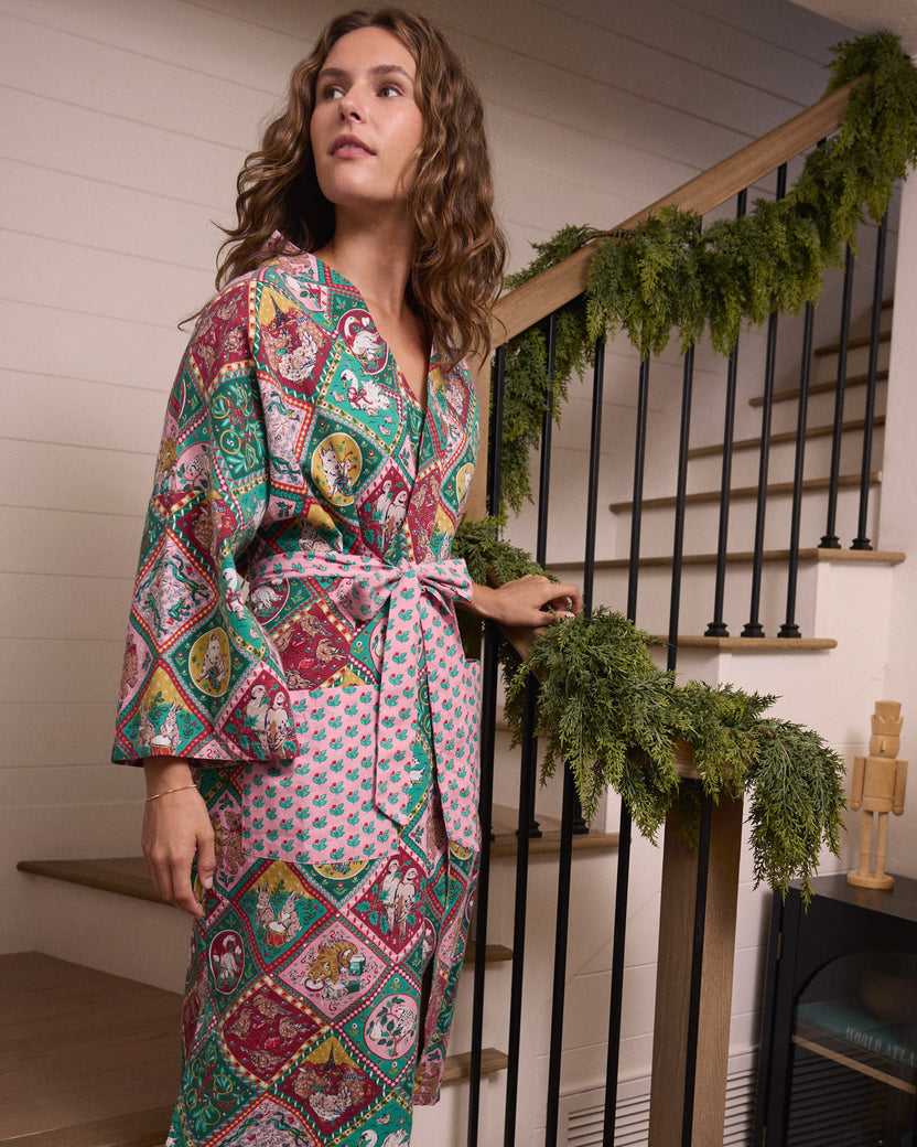 Person wearing a long robe with a multicolored 12 Days of Christmas print and a tied pink waist sash.