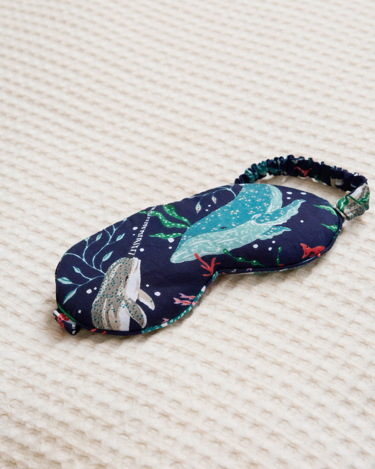 Arctic Sealife eye mask with whale print and elastic strap displayed on a light textured surface.