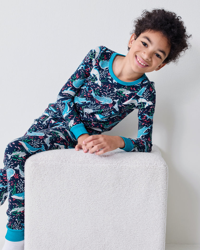 Child wearing the Arctic Sealife long-sleeve pajama set reclining on a white ottoman.