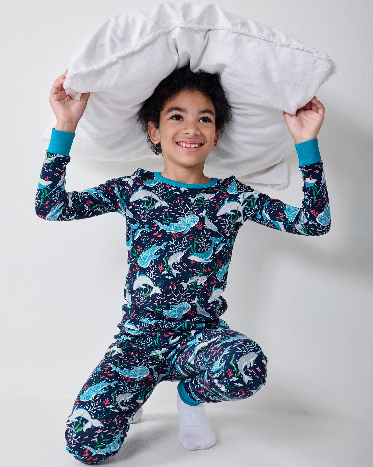 Child wearing the Arctic Sealife long-sleeve pajama set while kneeling and holding a white pillow overhead.