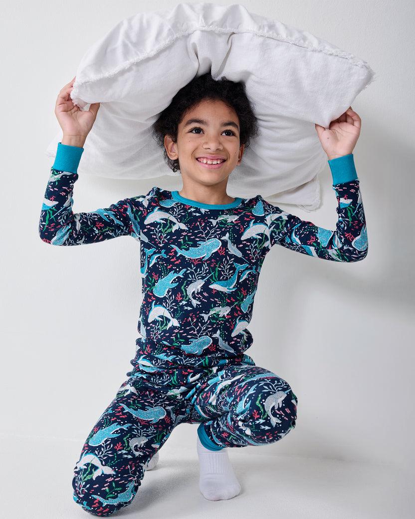 Child wearing the Arctic Sealife long-sleeve pajama set while kneeling and holding a white pillow overhead.