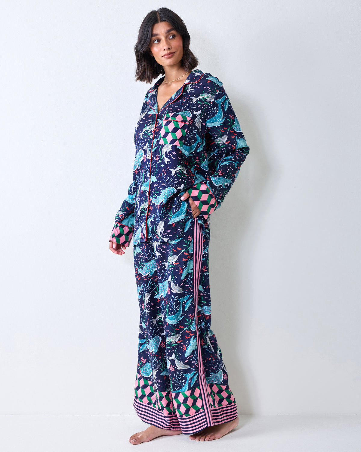 Person modeling a navy printed pajama shirt and wide-leg pants with geometric cuffs and striped hems.