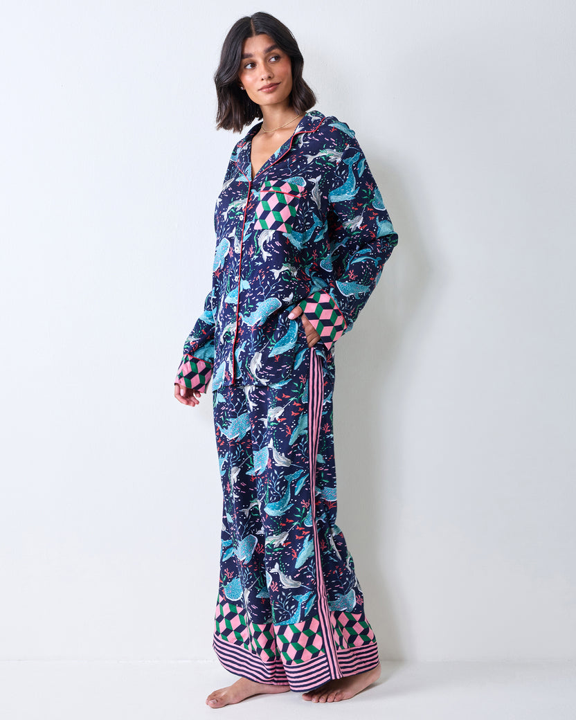 Person modeling a navy printed pajama shirt and wide-leg pants with geometric cuffs and striped hems.