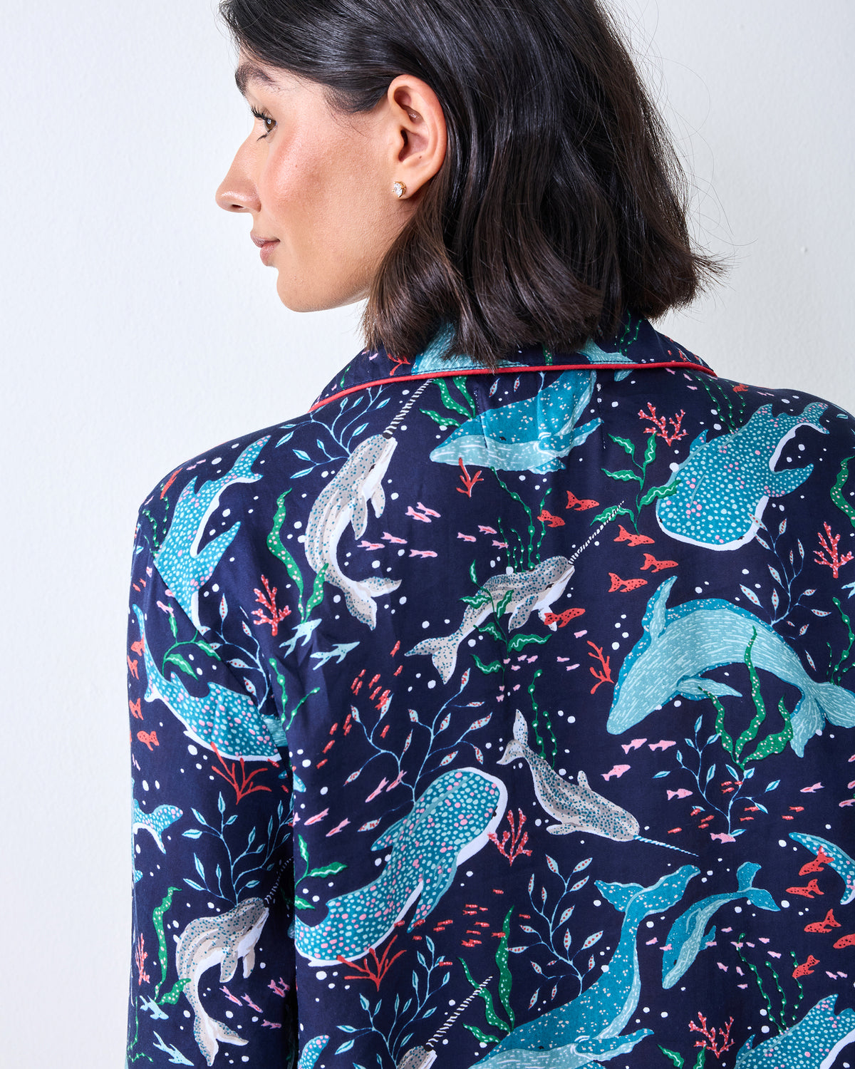 Close-up of the back of a dark blue pajama top with blue, white, green, and pink sea-life patterns