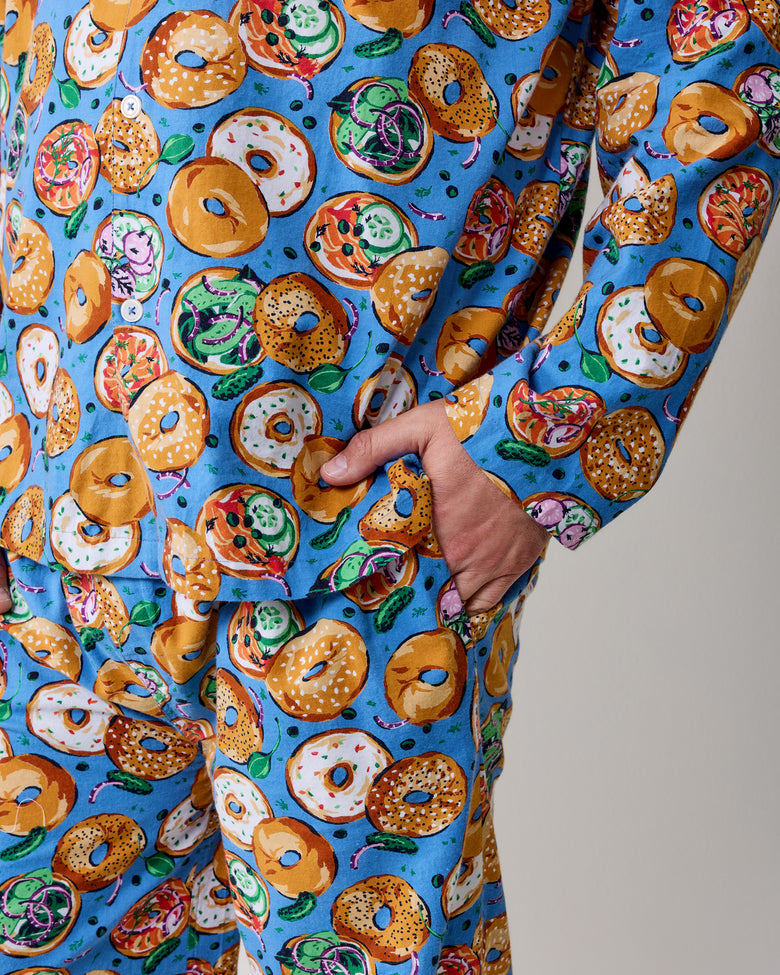 Close-up of blue bagel-print pajama fabric showing a button-front top and hand in a pocket.