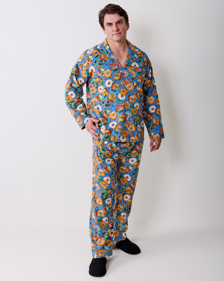 Full-length view of a person wearing a blue bagel-print long-sleeve pajama set with black slippers.