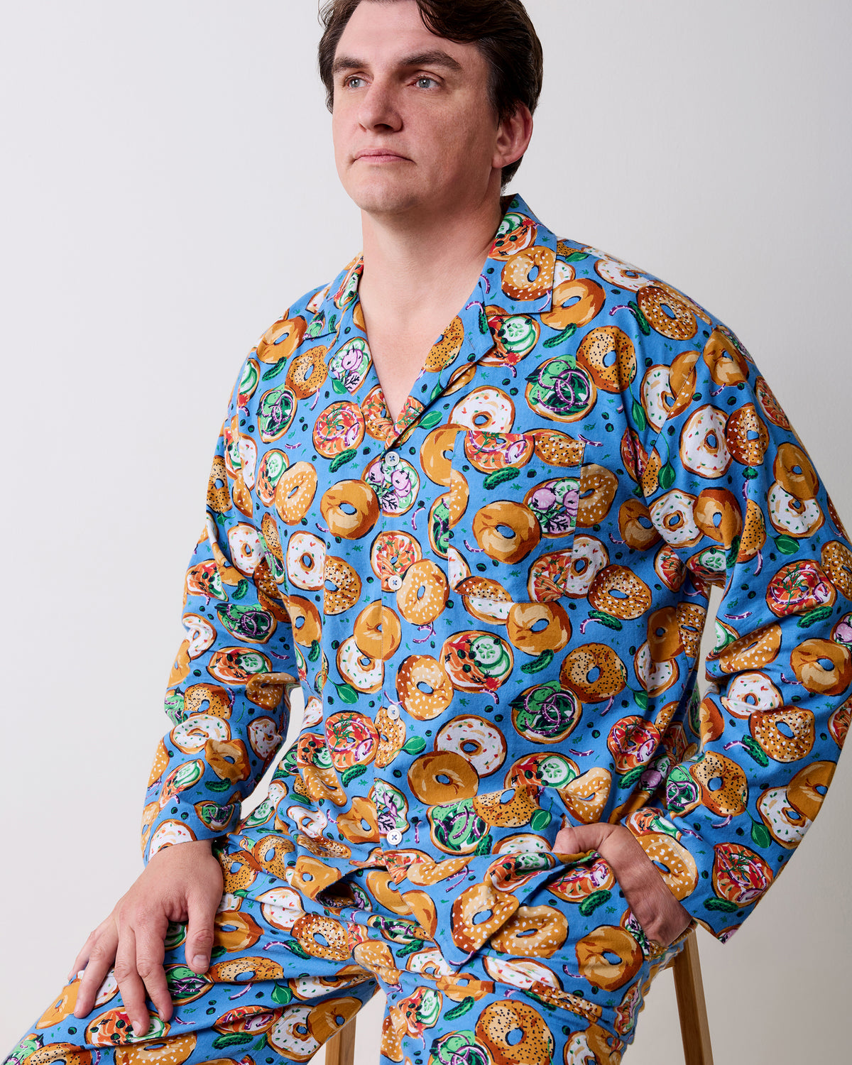 Side view of a person seated in a blue bagel-print long-sleeve pajama set.