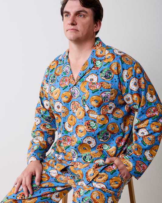 Side view of a person seated in a blue bagel-print long-sleeve pajama set.