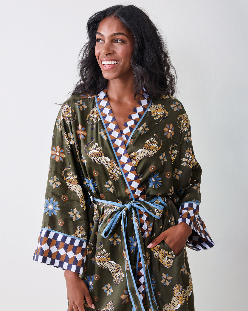 Front close-up of the olive robe showing the leopard-and-floral print, geometric neckline and cuffs, blue piping, and tied belt.