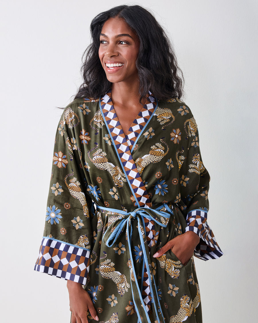 Front close-up of the olive robe showing the leopard-and-floral print, geometric neckline and cuffs, blue piping, and tied belt.