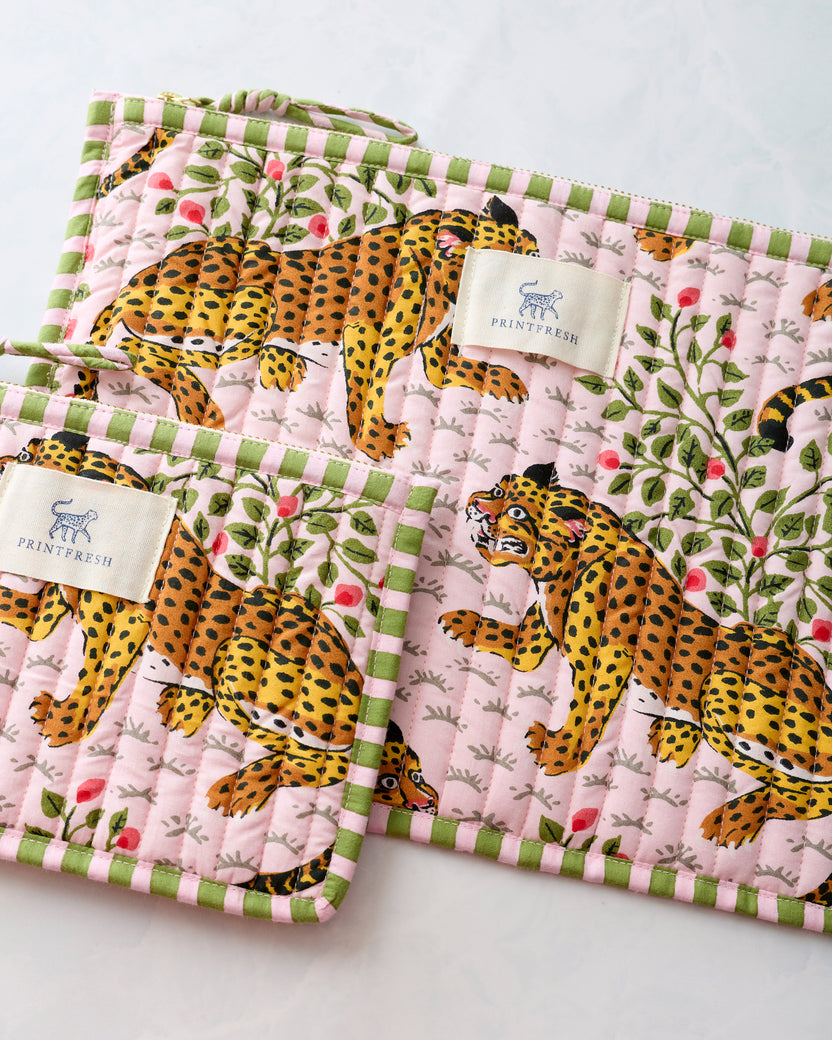 Close-up of two pink quilted zippered pouches with leopard and leafy floral print, green trim, and Printfresh labels.
