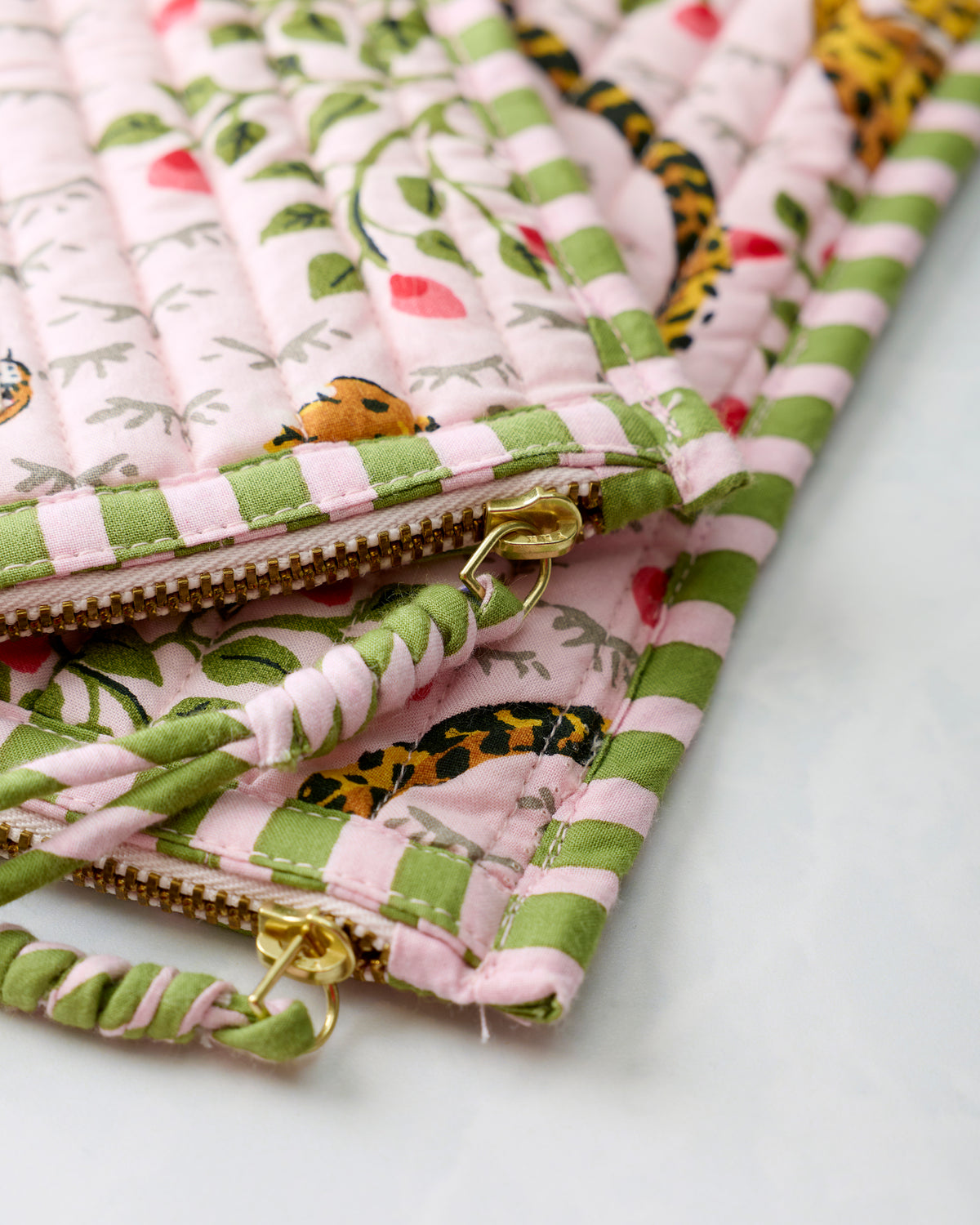 Close-up of the pouches' gold zipper closures and matching striped fabric pulls.