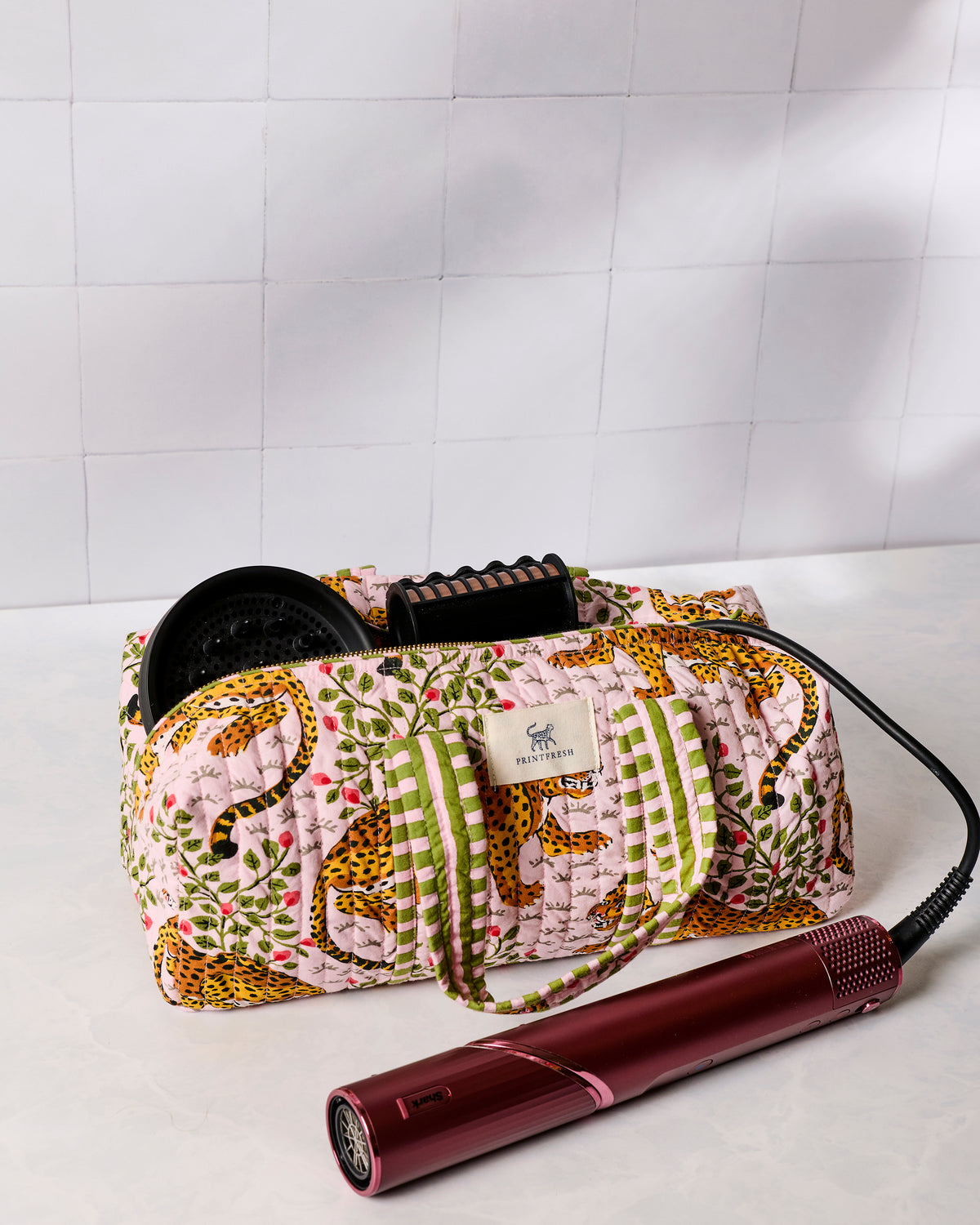 Pink leopard-print quilted hair tool travel case with a red styling tool placed in front
