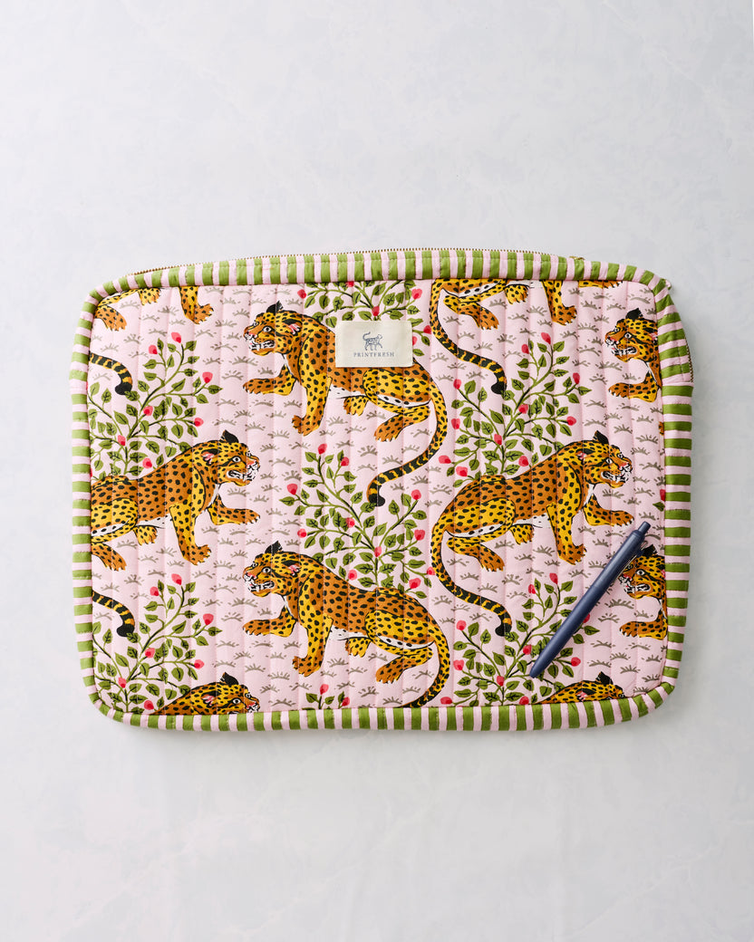 Pink leopard-print quilted laptop sleeve with green striped trim, shown with a pen on the front