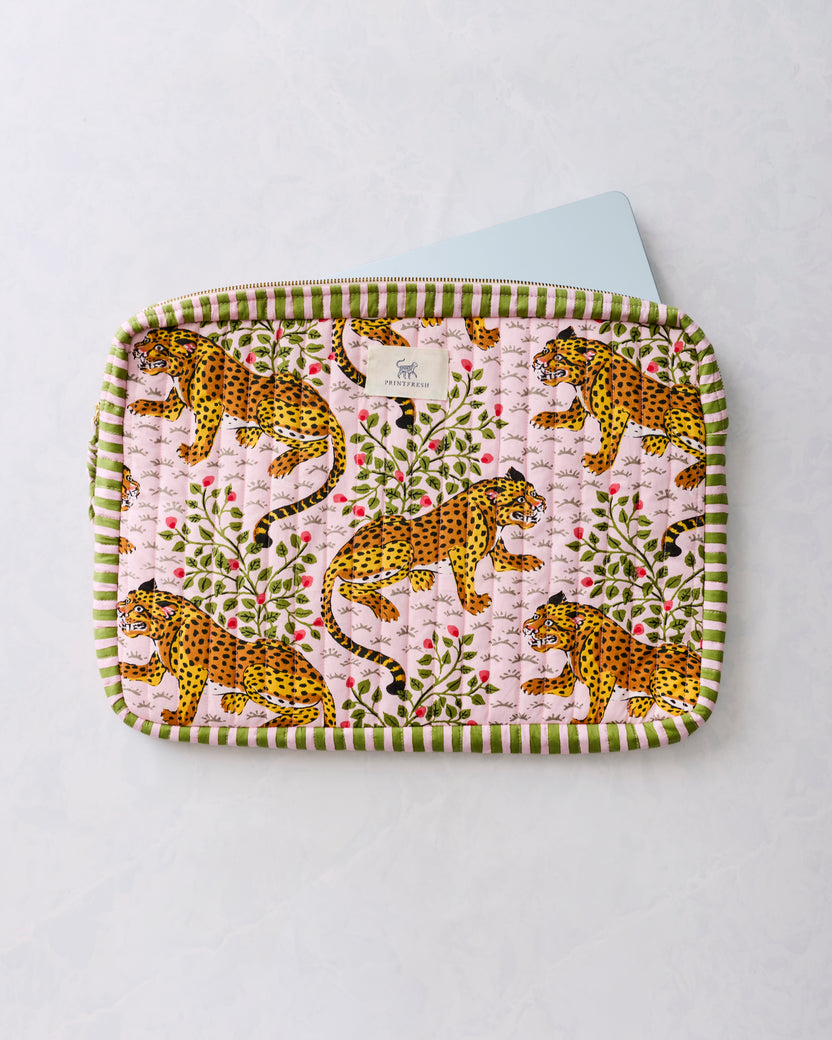 Quilted laptop sleeve with a leopard-and-floral print, green striped trim, and a laptop partly inserted at the top.