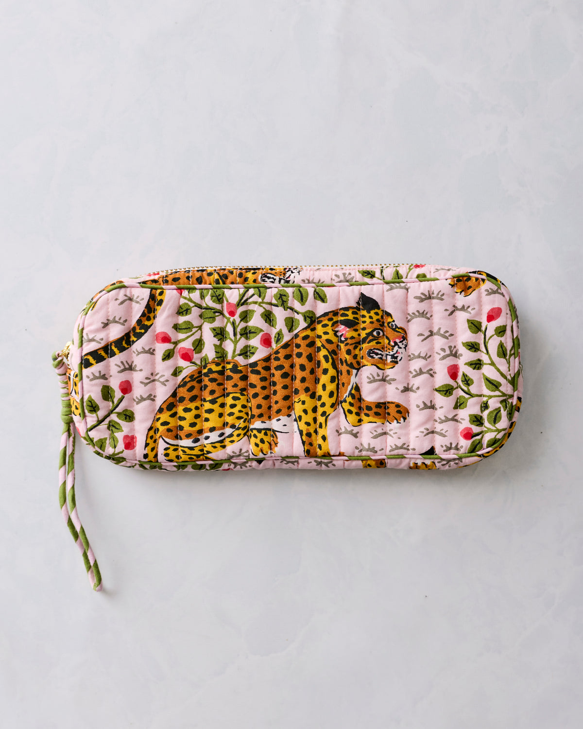 Closed pink quilted sunglasses case with a leopard and botanical print and a wrist strap