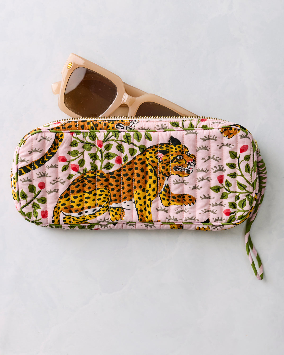 Pink quilted leopard-print sunglasses case with beige sunglasses resting partly inside