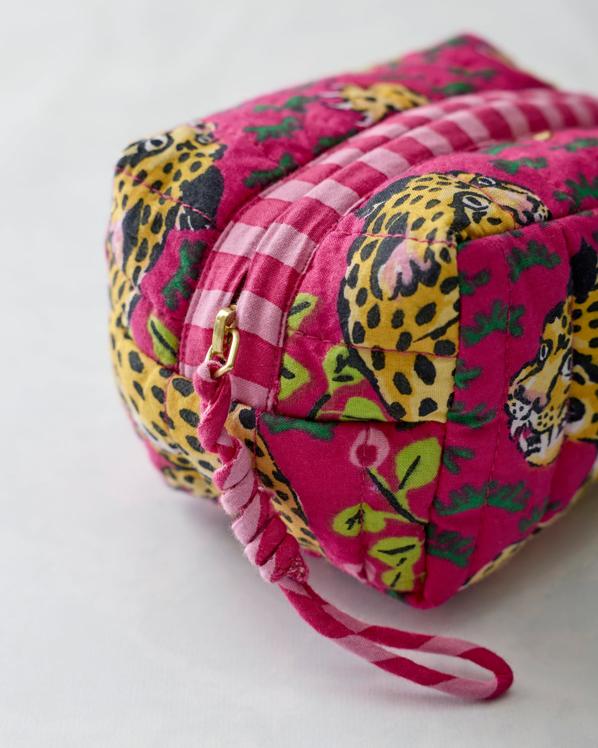 Hot pink quilted leopard-print wristlet shown from the back with a zipper and ruched wrist strap.