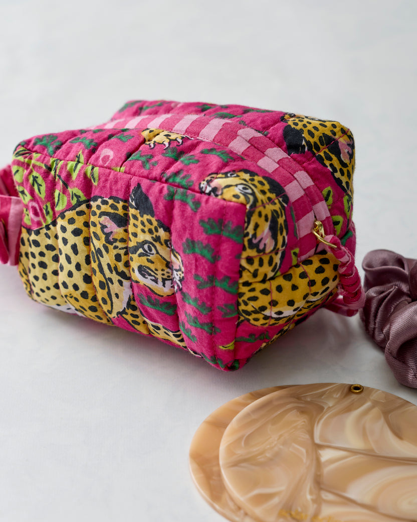 Hot pink quilted leopard-print wristlet shown from the side with its ruched strap and zipper pull.