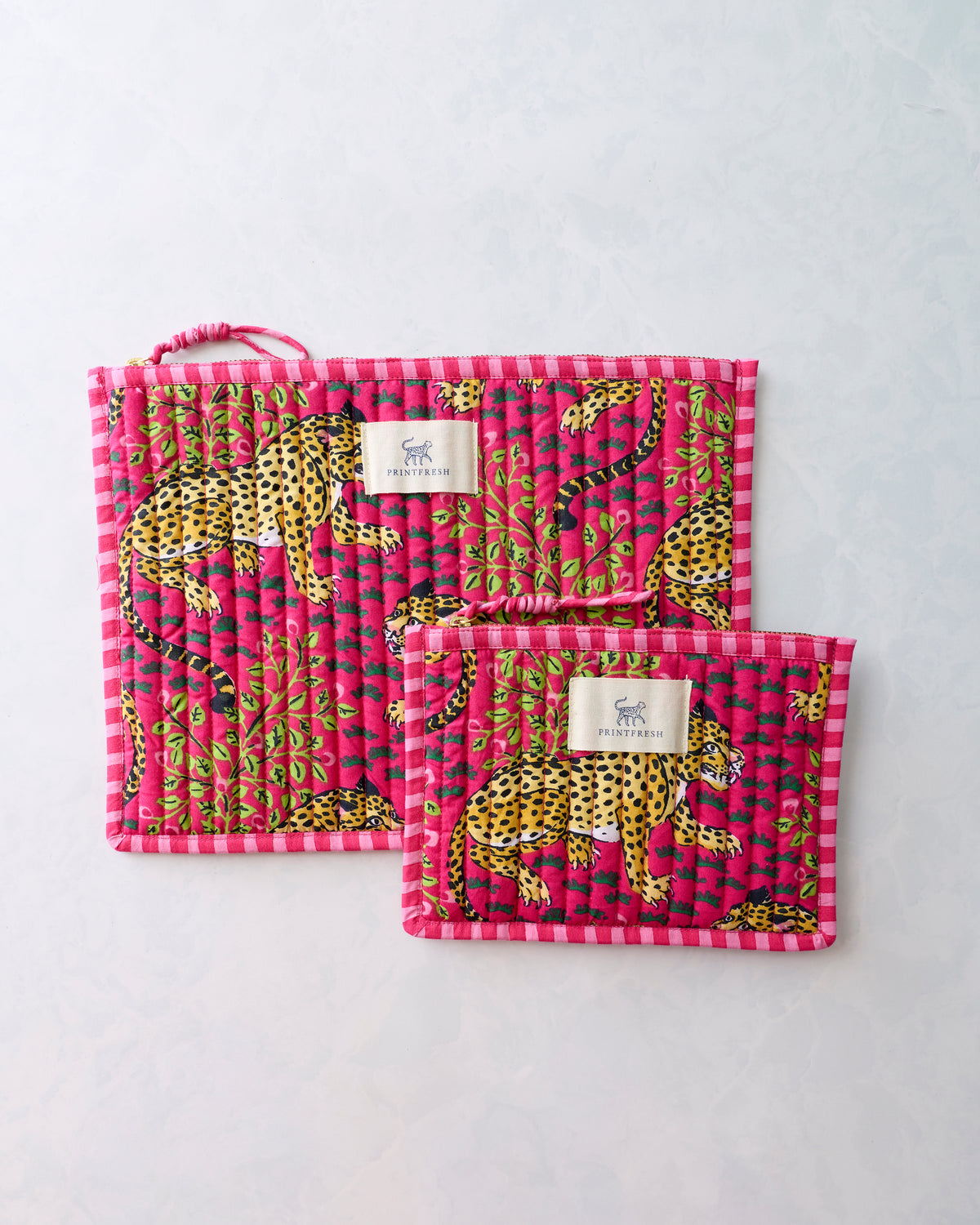 Two hot pink flat pouches with yellow leopard and green foliage print, shown overlapping with their Printfresh labels visible.