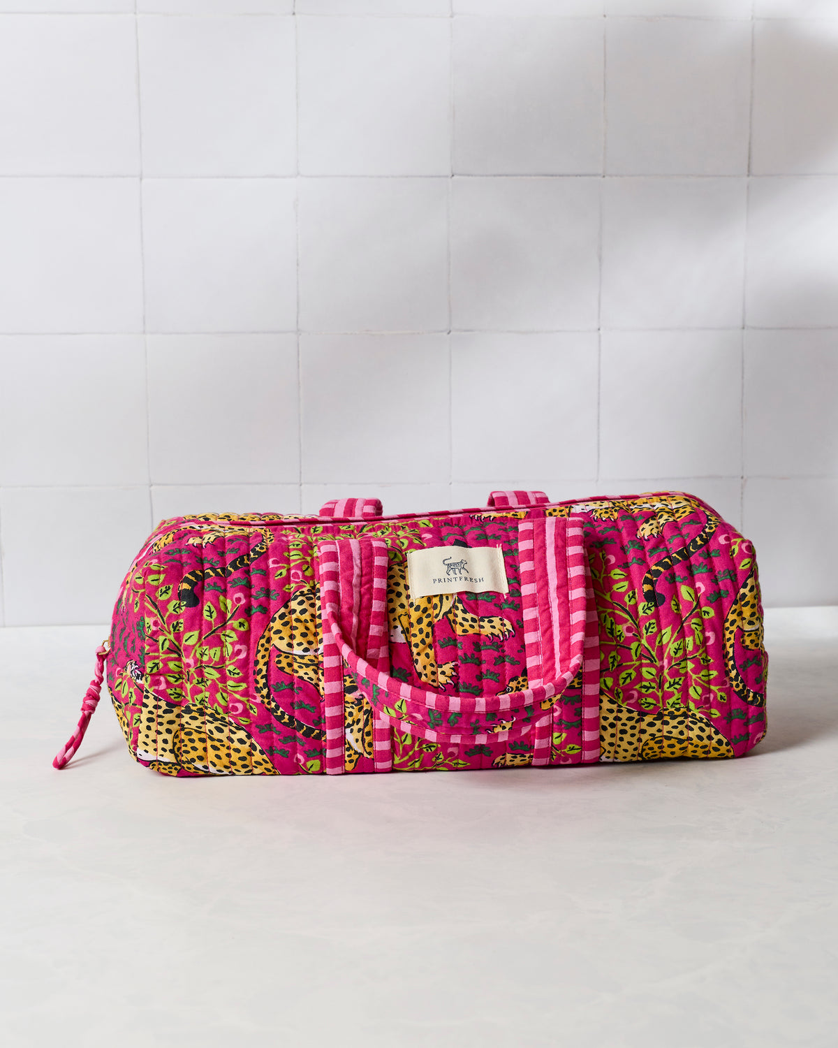 Closed hot pink quilted hair tool travel case with handles, zipper, leopard and foliage print, and Printfresh label.