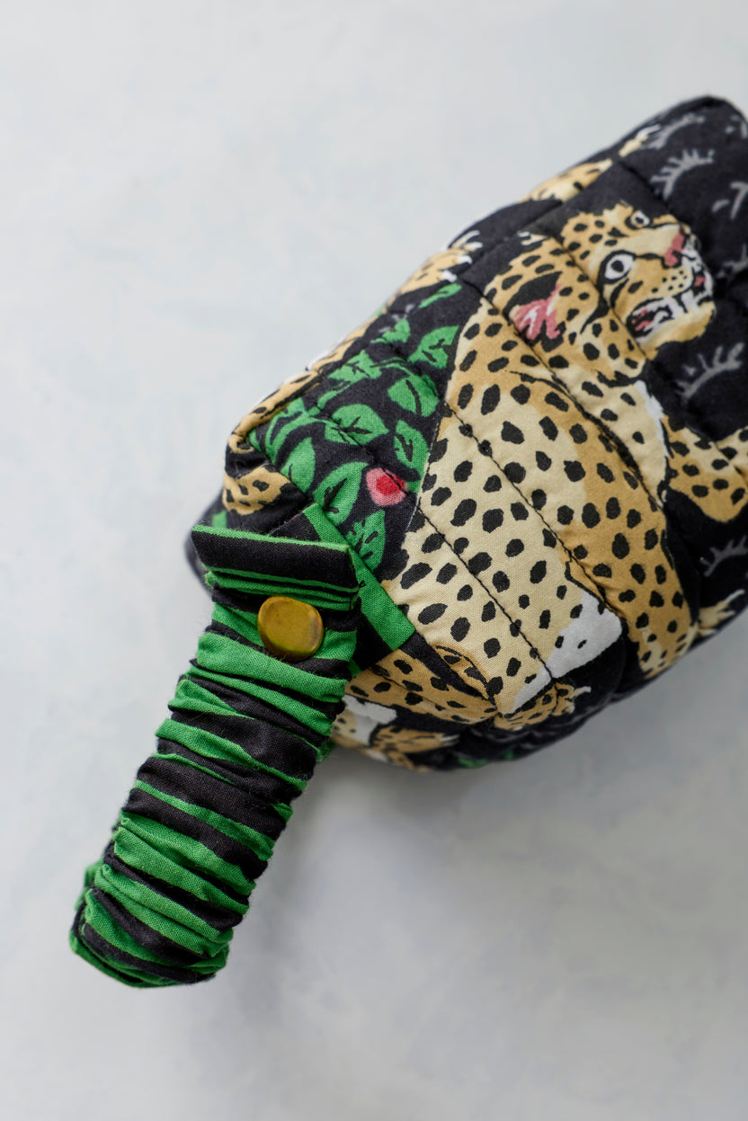 Close-up of the quilted Bagheera Ink essentials wristlet with leopard and leafy print and a green-and-black striped wrist strap.