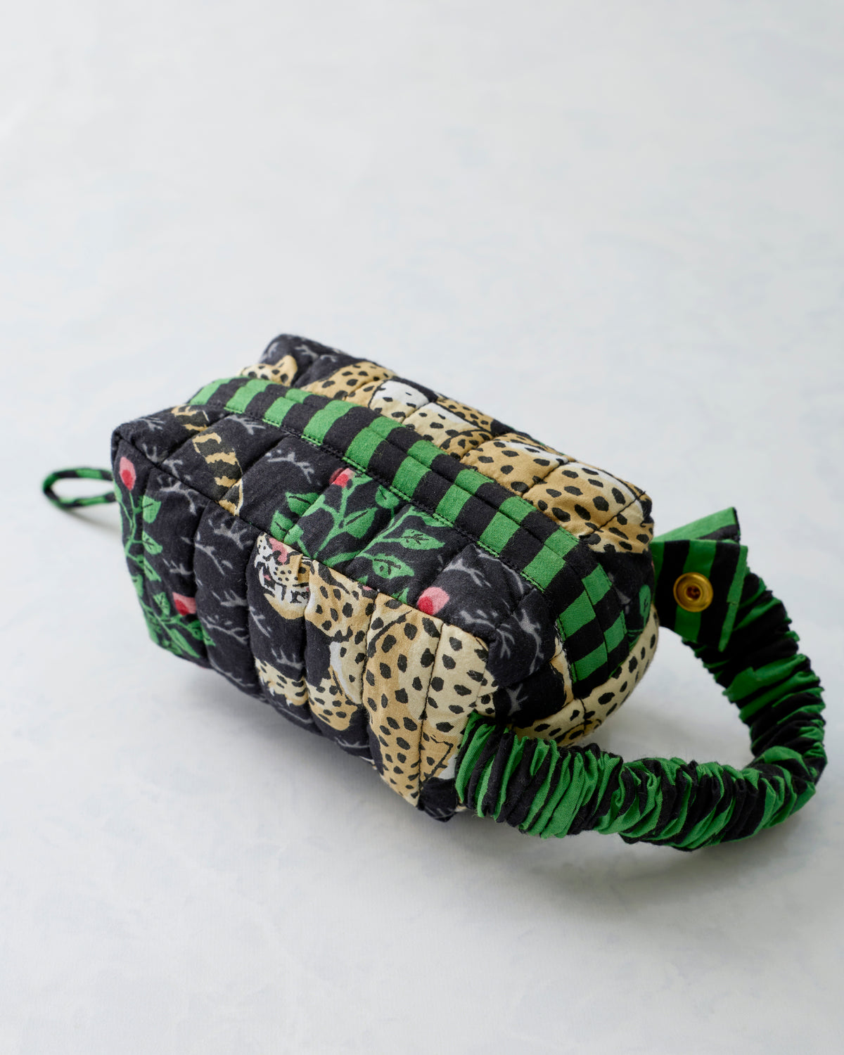 Rear three-quarter view of the Bagheera Ink quilted essentials wristlet with leopard print and a green-and-black striped strap.
