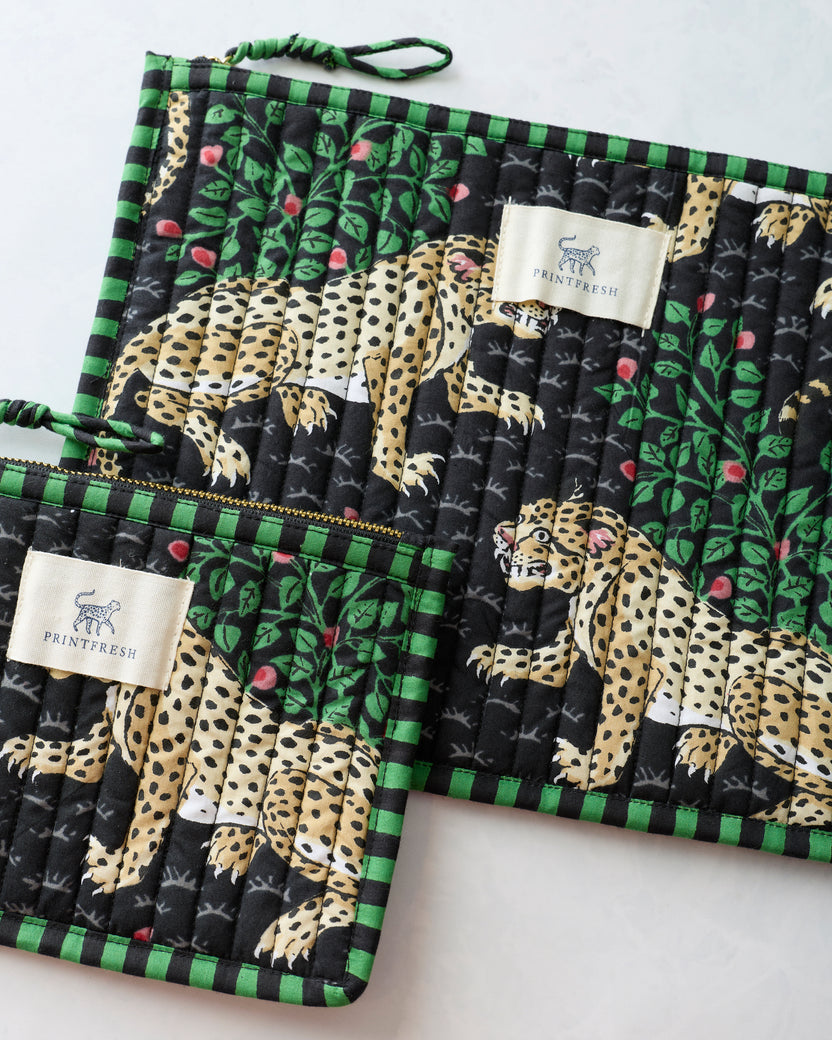 Close-up of two Bagheera Ink flat pouches showing the leopard-and-leaf print, quilted stitching, zippers, and Printfresh labels.