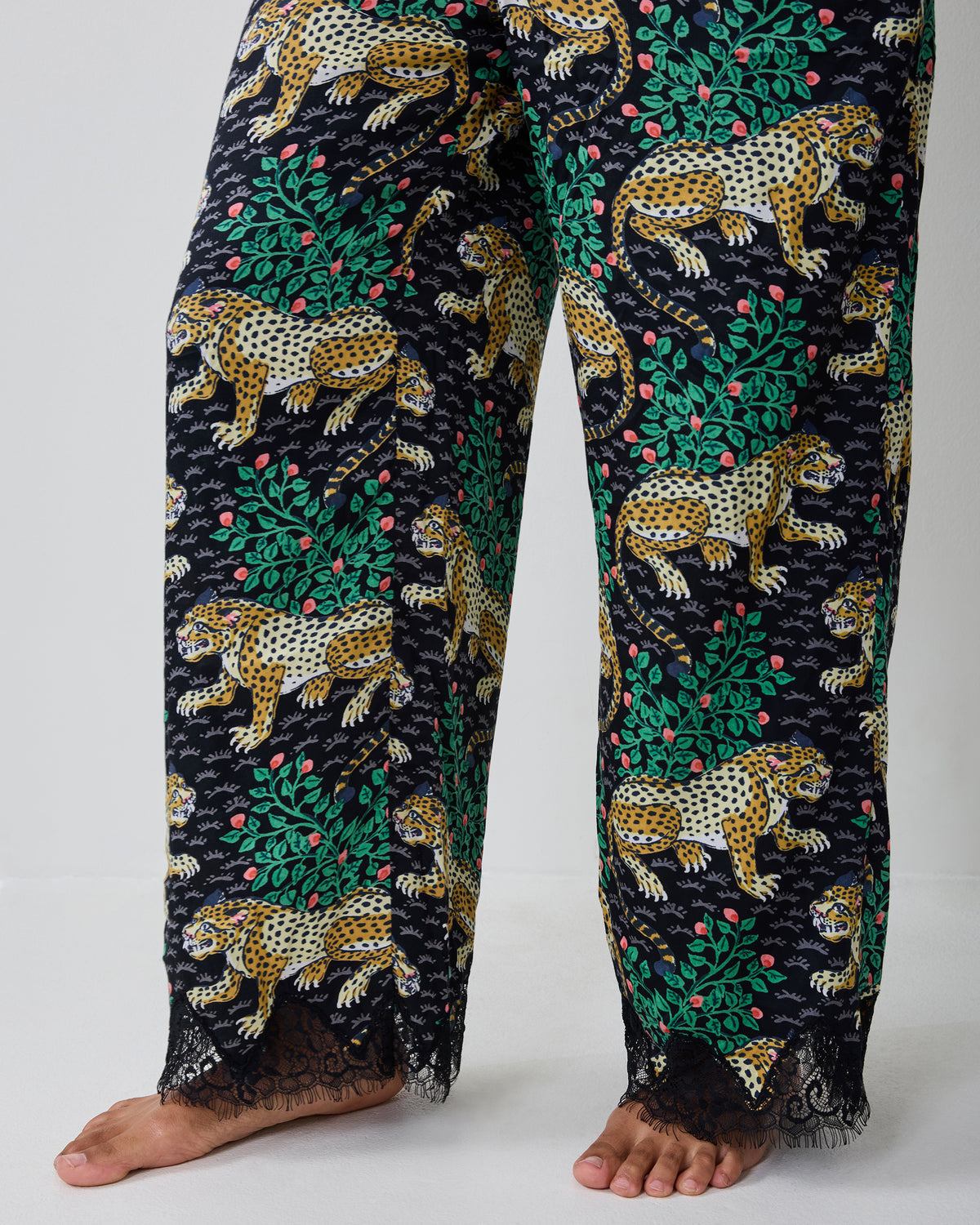 Close-up of the Bagheera Ink pajama pants, showing the leopard-and-leaf print and black lace trim at the ankles.