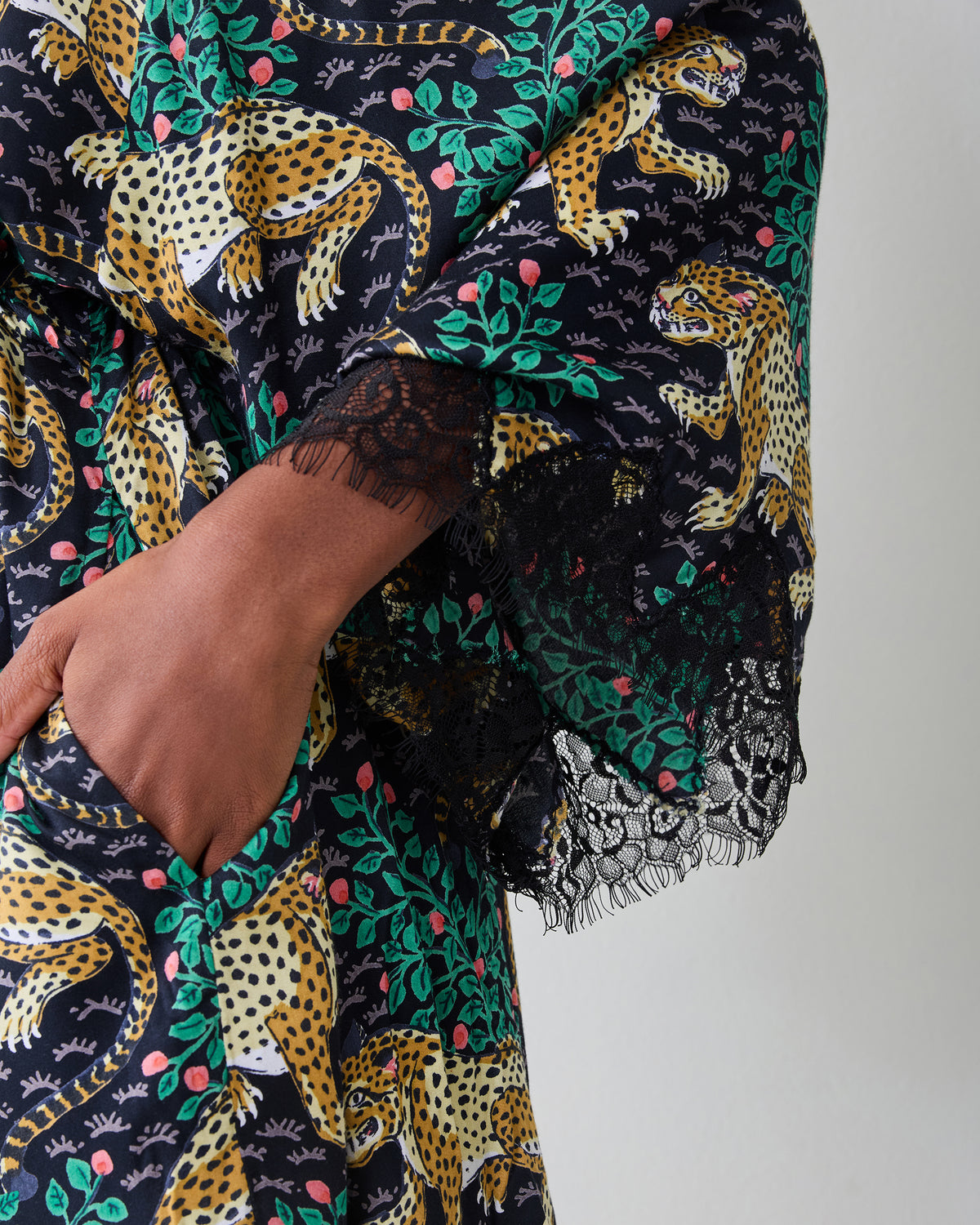 Close-up of the Bagheera Ink lace robe sleeve and pocket, showing the leopard-and-leaf print and black lace trim.