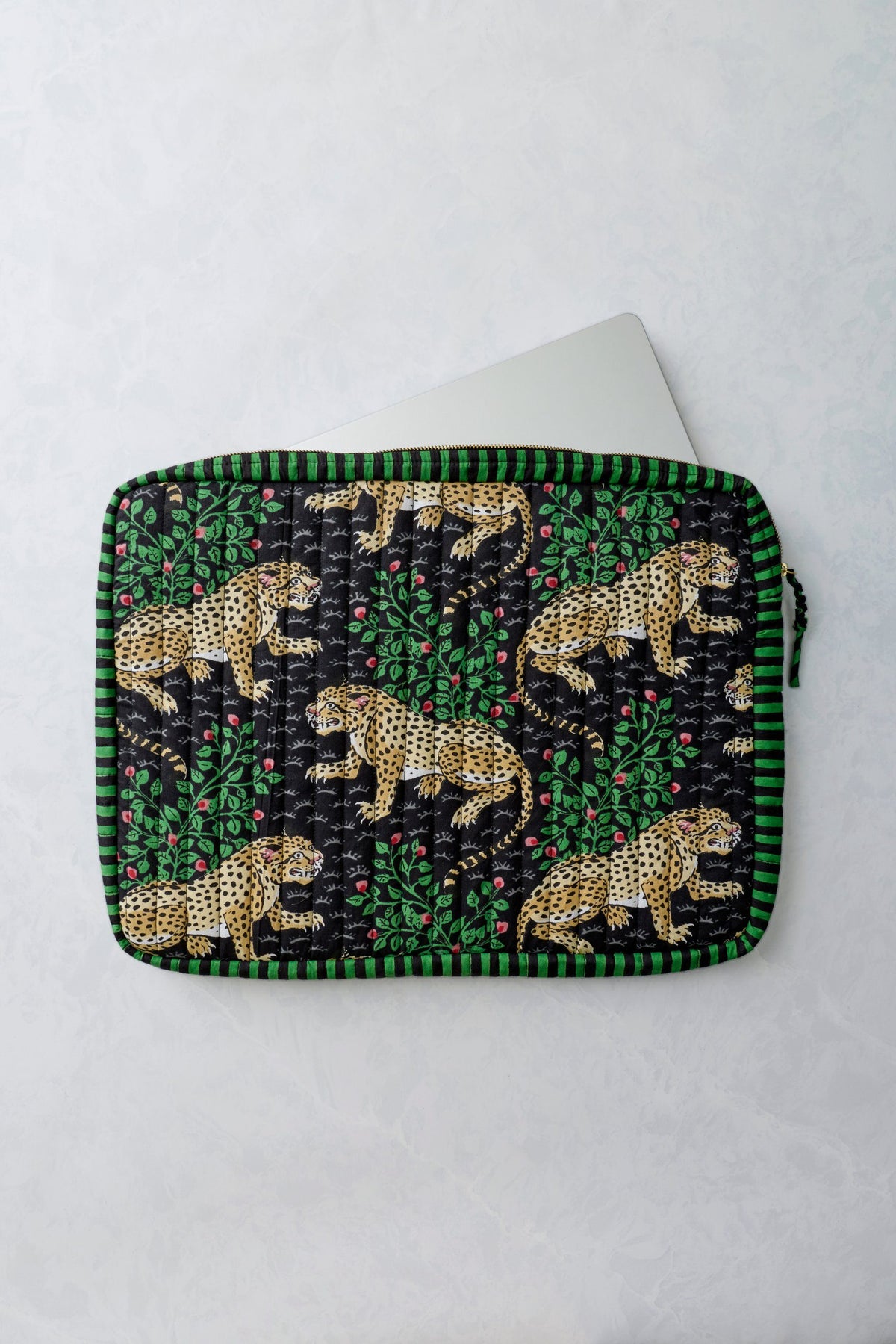Bagheera Ink quilted laptop sleeve shown open with a white laptop partially inside; leopard and leafy print covers the sleeve.