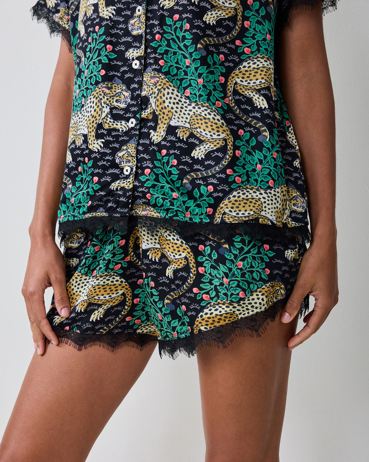 Close-up of the Bagheera Eco Satin Maryanne Set in Ink, showing the button-front top hem and matching shorts with lace trim.