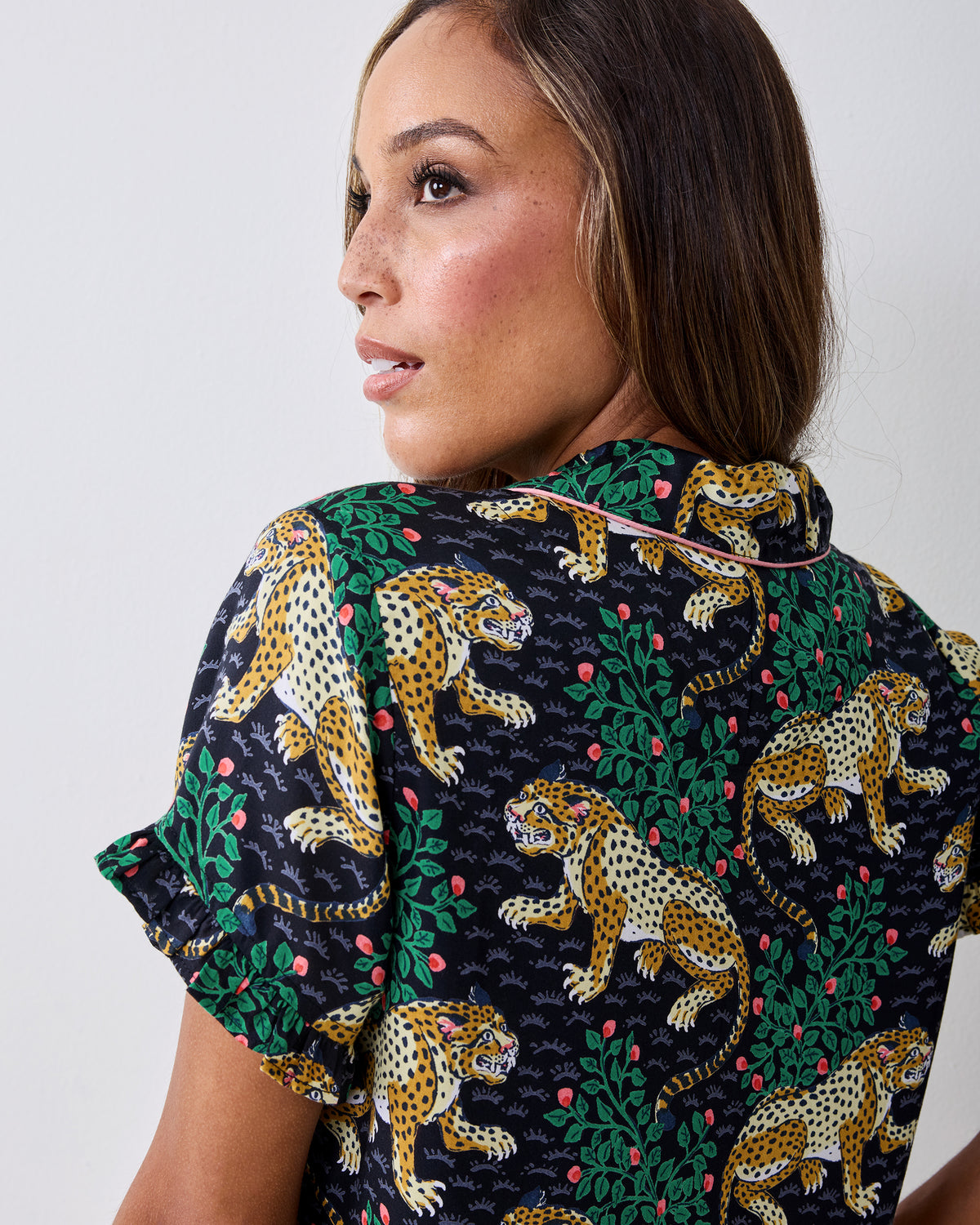 Back close-up of the Bagheera ink pajama top, showing the leopard-and-foliage print, pink piping, collar, and ruffled sleeve edge.