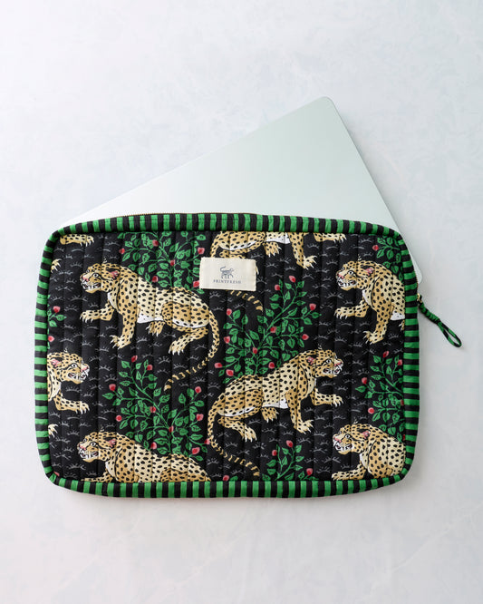 Black quilted leopard-print case with green striped edging, shown with the corner of a white laptop inside.