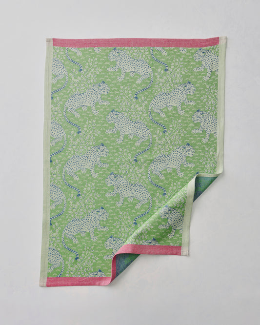 Green Bagheera jacquard tea towel with a repeating spotted big-cat pattern and pink edging, shown with one corner folded back.