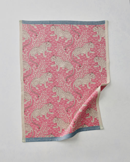 Hot pink Bagheera jacquard tea towel with a repeating leopard-and-floral pattern, shown flat with one corner folded back.