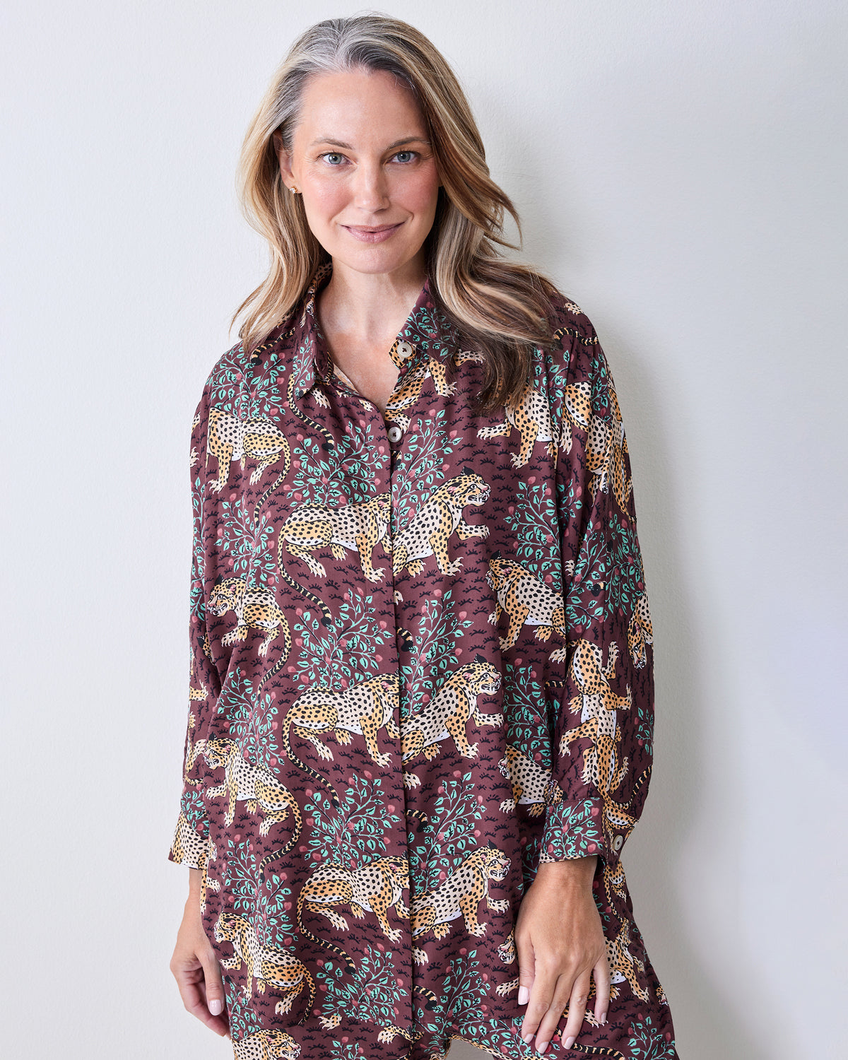 Front view of a raisin pajama set with leopard-and-leaf print, a collared button-front top, long sleeves, and wide-leg pants.