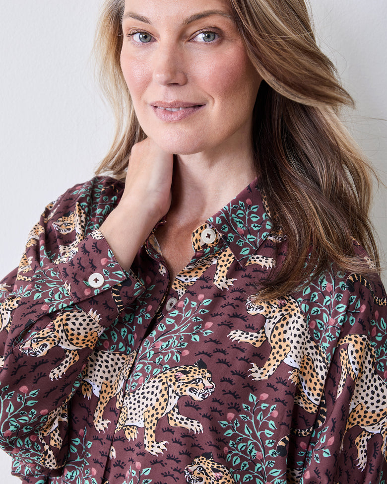 Close-up of the raisin pajama top showing its leopard-and-leaf print, collar, front buttons, and buttoned cuff.