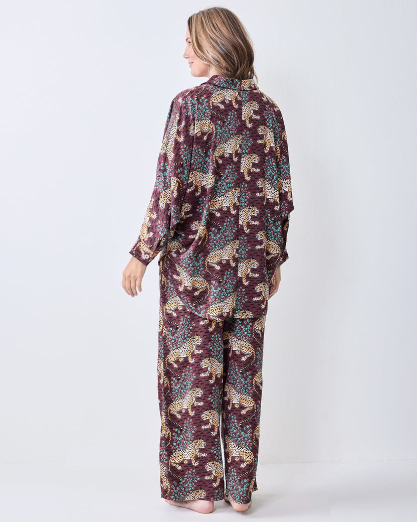Back and side view of a leopard-print satin pajama set with a loose button-front shirt and wide-leg pants.