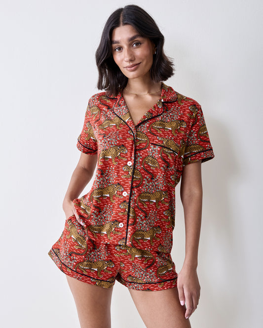 Front view of a person wearing the Scarlet Bagheera short pajama set with a short-sleeved button-front top and matching shorts in a leopard and botanical print.