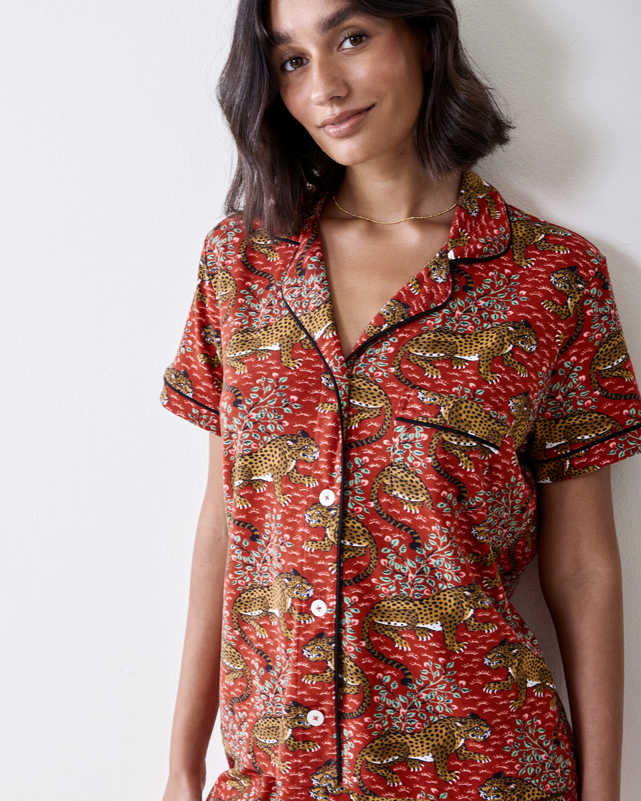 Close-up of the scarlet Bagheera short pajama top with leopard-and-leaf print, notched collar, black piping, and button front.
